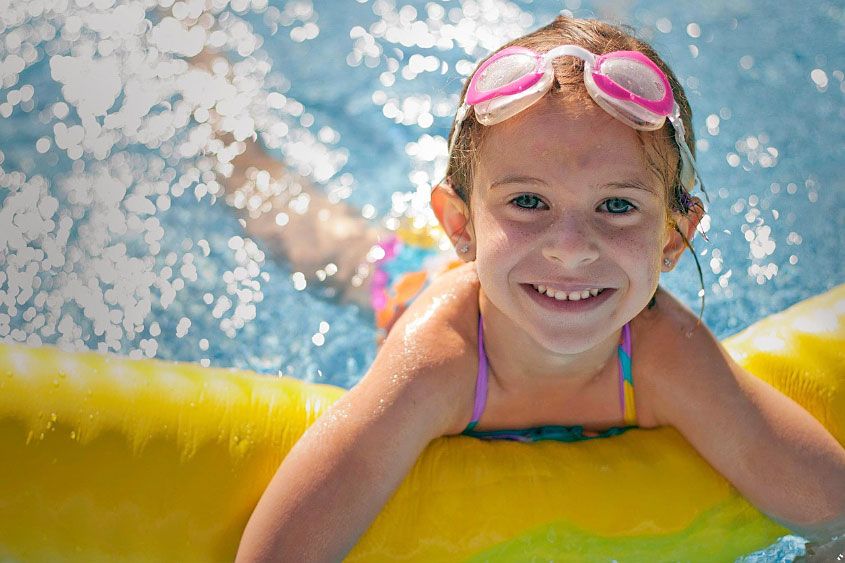little girl smiling in a swimming pool