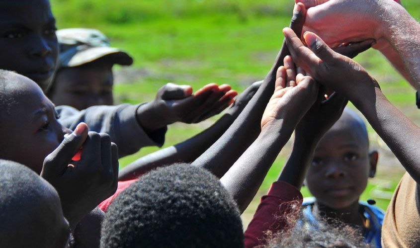 children reaching out to a person's hand