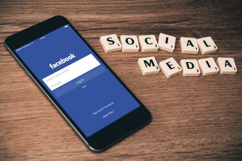 social media scrabble tiles with Facebook on mobile screen