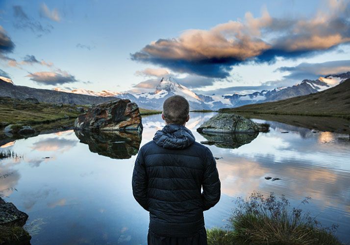 man looking over a lake with mountain background