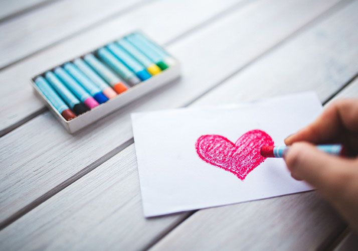 person drawing heart with crayon
